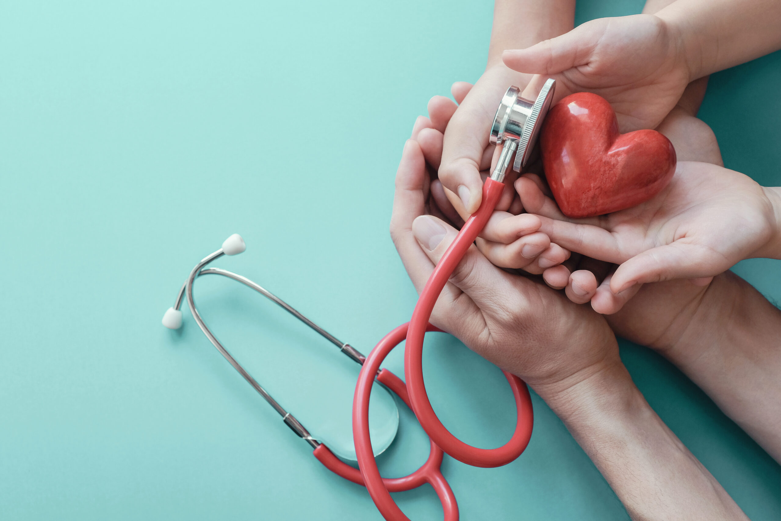 Family hands holding red heart with stethoscope